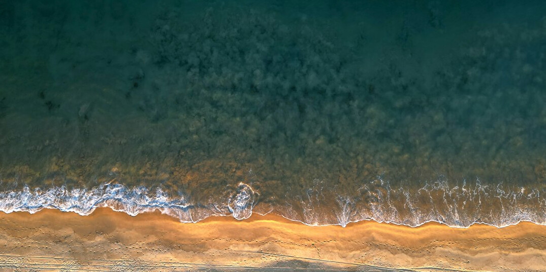 Aerial drone view of a golden-hour coastline with turquoise ocean waves